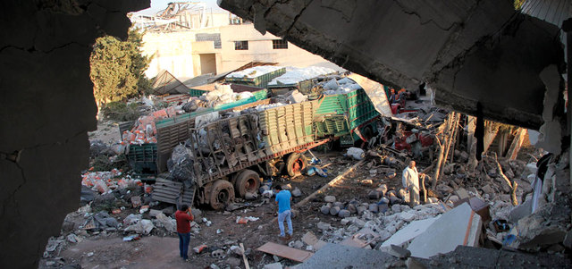سوريون ينظرون إلى المساعدات المتناثرة من قافلة مساعدات تعرضت لقصف في بلدة أورم الكبرى. أ.ف.ب
