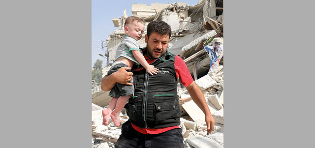 رجل يحمل طفلاً بعد انتشاله من تحت أنقاض مبنى دمر بغارة لقوات النظام على حي القاطرجي بحلب. أ.ف.ب
