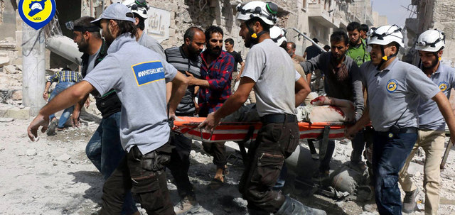 عناصر من الدفاع المدني يسعفون مصاباً بقصف للنظام على حي الصاخور في حلب. أ.ب