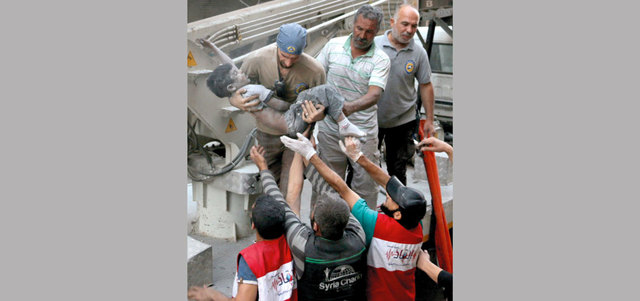 متطوعو الدفاع المدني يُخرجون جثة فتى من تحت أنقاض مبنى تهدم بغارة لقوات النظام على حي الشعار في حلب. أ.ف.ب