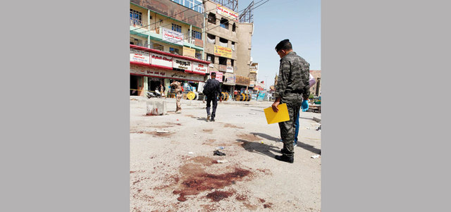 قوات أمن تعاين موقع هجوم انتحاري في حي بغداد الجديدة. أ.ف.ب
