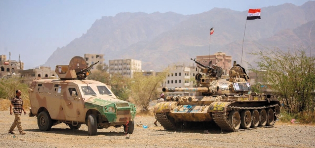يمني يسير بجوار قوات من الجيش اليمني في تعز.  أرشيفية