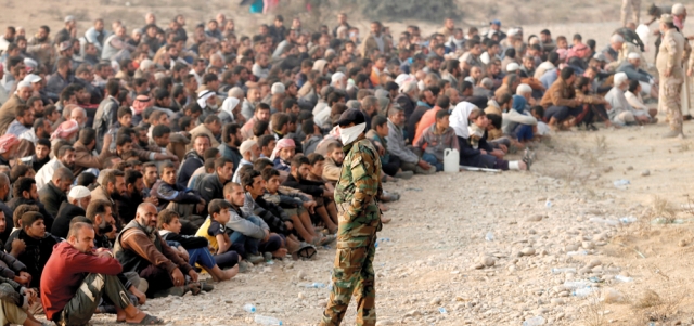 جنود عراقيون أمام عشرات النازحين في القيارة شرق الموصل. رويترز