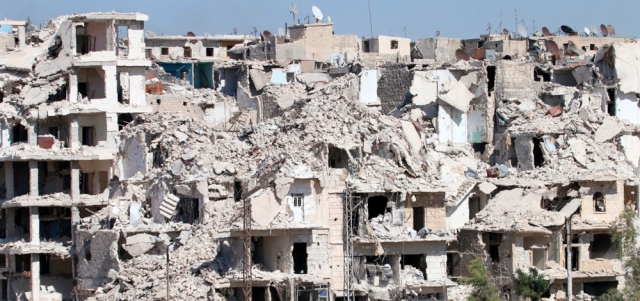 سوريون يمرّون أمام أنقاض المباني التي تهدمت في حي بني زيد على المشارف الشمالية لمدينة حلب. أ.ف.ب