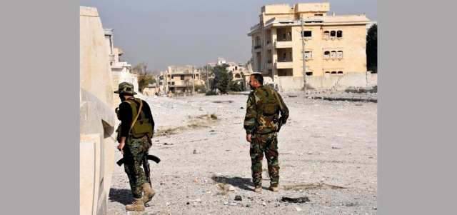 صورة لجنديين من قوات النظام خلال عملية تفتيش المباني في ضاحية الأسد غرب حلب. إي.بي.إيه