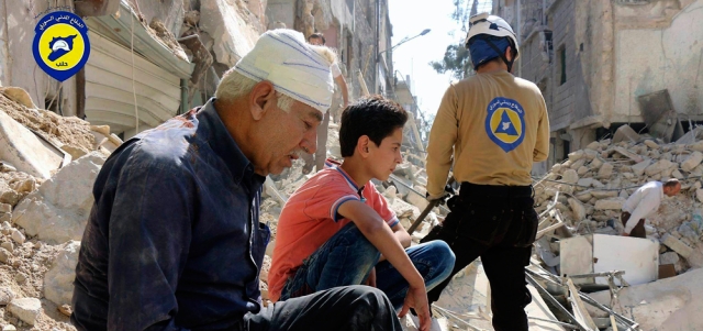 سكان يجلسون بين أنقاض مباني تهدمت بغارات لقوات النظام على أحياء حلب الشرقية. أ.ب