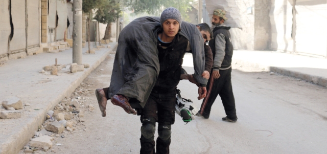 متطوع يحمل رجلاً أصيب بغارة لقوات النظام على أحياء حلب الشرقية. أ.ف.ب