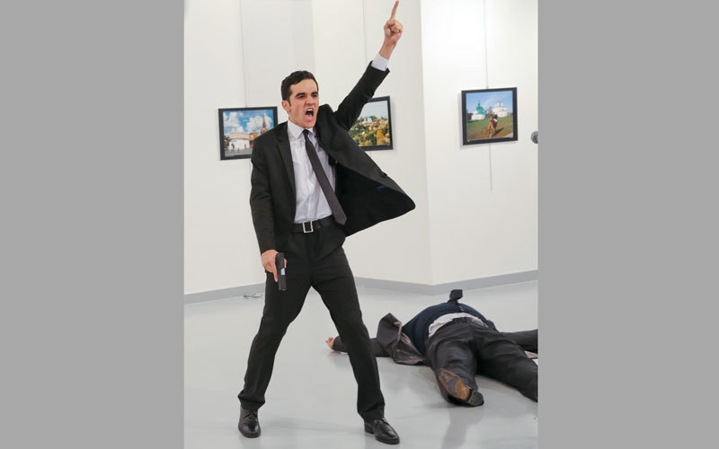 صورة تظهر السفير الروسي ممداً أرضاً وبالقرب منه القاتل يحمل مسدساً. أ.ب