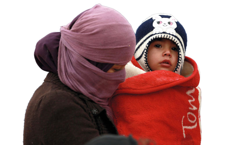 عراقية من الموصل تحمل طفلتها التي حاصرها البرد أثناء نزوحها من مدينتها طلباً للأمن في مكان آخر.  أرشيفية