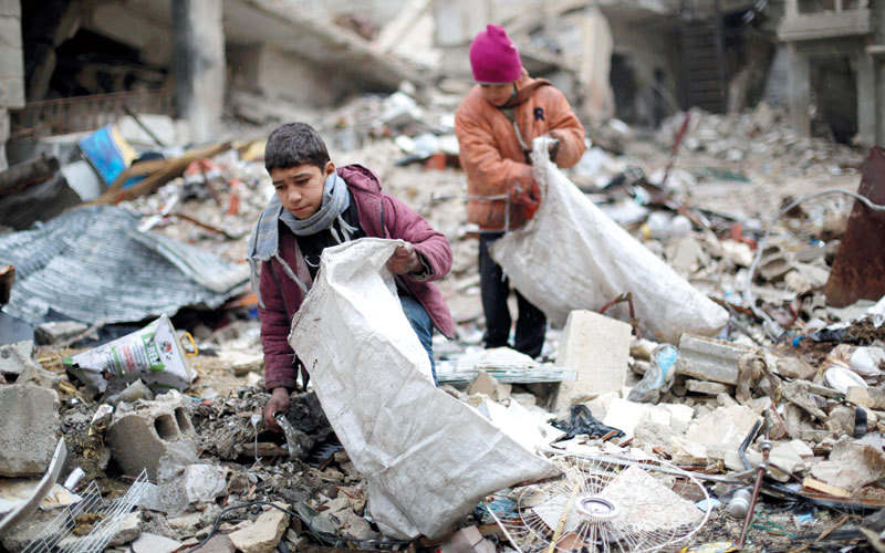 فتيان يجمعان الخشب من بين الأنقاض لاستخدامه في التدفئة والطهي في بلدة زملكا الخاضعة للمعارضة بريف دمشق. أ.ف.ب