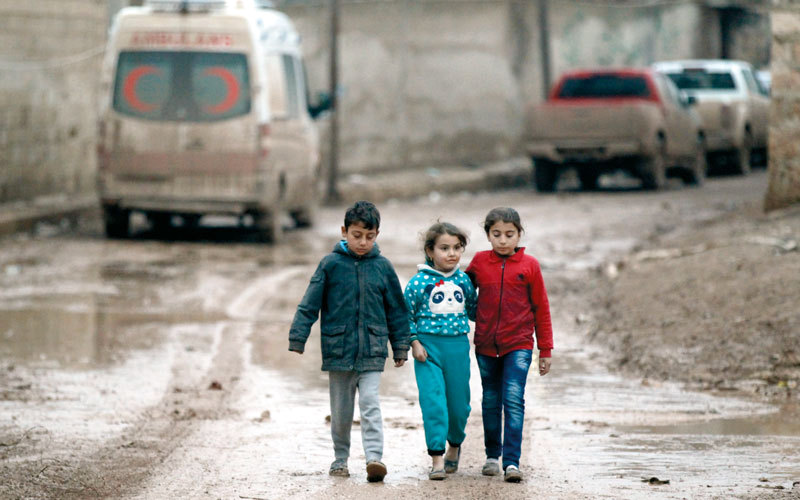 أطفال سوريون يمشون بالقرب من سيارة إسعاف متوقفة في بلدة الراعي بمحافظة حلب. رويترز