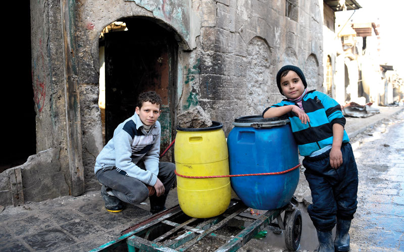 صبيَّان حول عربة لجلب مياه الشرب شرق حلب. أ.ف.ب