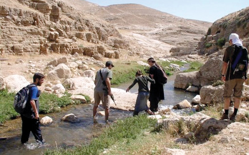 مستوطنون يستجمون في أودية وادي القلط وهم يحملون السلاح.