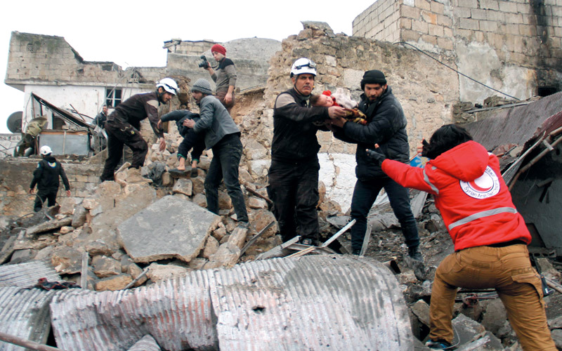 متطوعون ينقذون طفلين من مبنى تضرر بغارة للنظام استهدفت محطة للحافلات في إدلب. أ.ف.ب