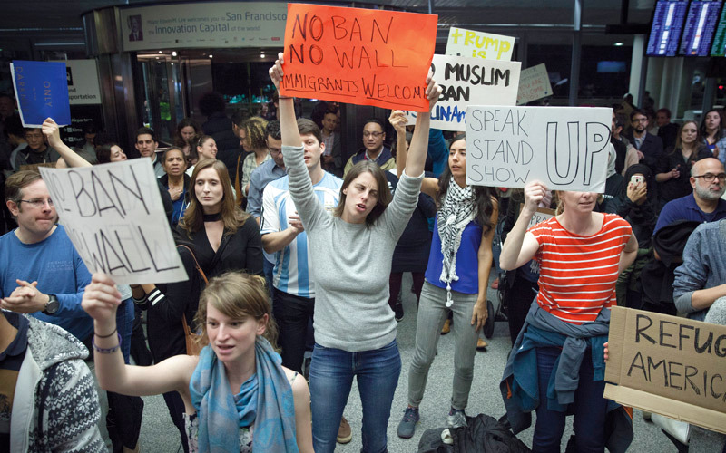 متظاهرون يحملون لافتات معادية لسياسة ترامب عند المدرج الرابع لمطار سان فرانسيسكو.  إي.بي.إيه