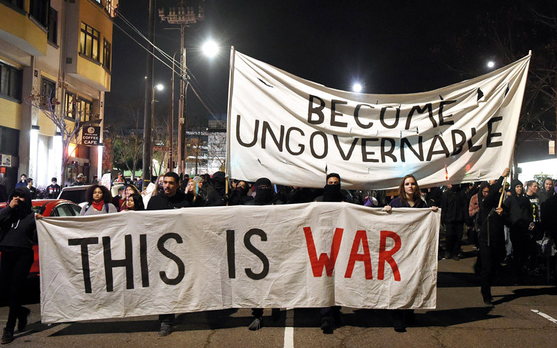 المحتجون يحملون لافتات كُتب عليها «إنها الحرب» خلال مظاهرة ضد قدوم يانوبولوس إلى حرم الجامعة. أ.ف.ب