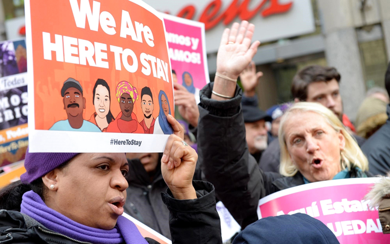 لافتة تقول «نحن هنا لنبقى» رفعها مهاجرون خلال تظاهرة في بوسطن. أ.ف.ب