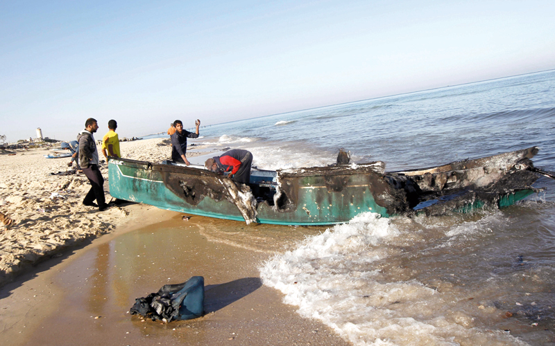فلسطينيون يعاينون قارب صيد دمرته البحرية الإسرائيلية في غزة. أ.ف.ب