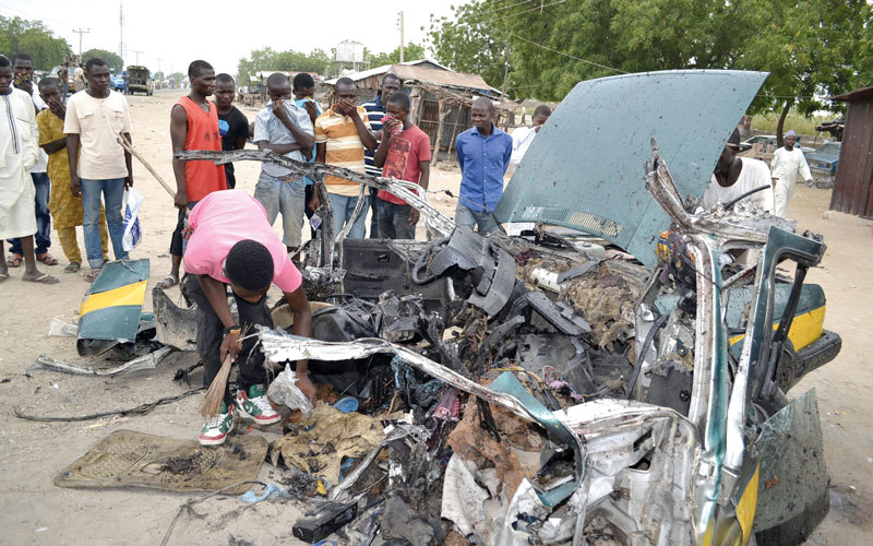 نيجيريون يتجمعون حول حطام سيارة بعد تنفيذ هجوم انتحاري في مدينة مايدوغوري. أ.ب